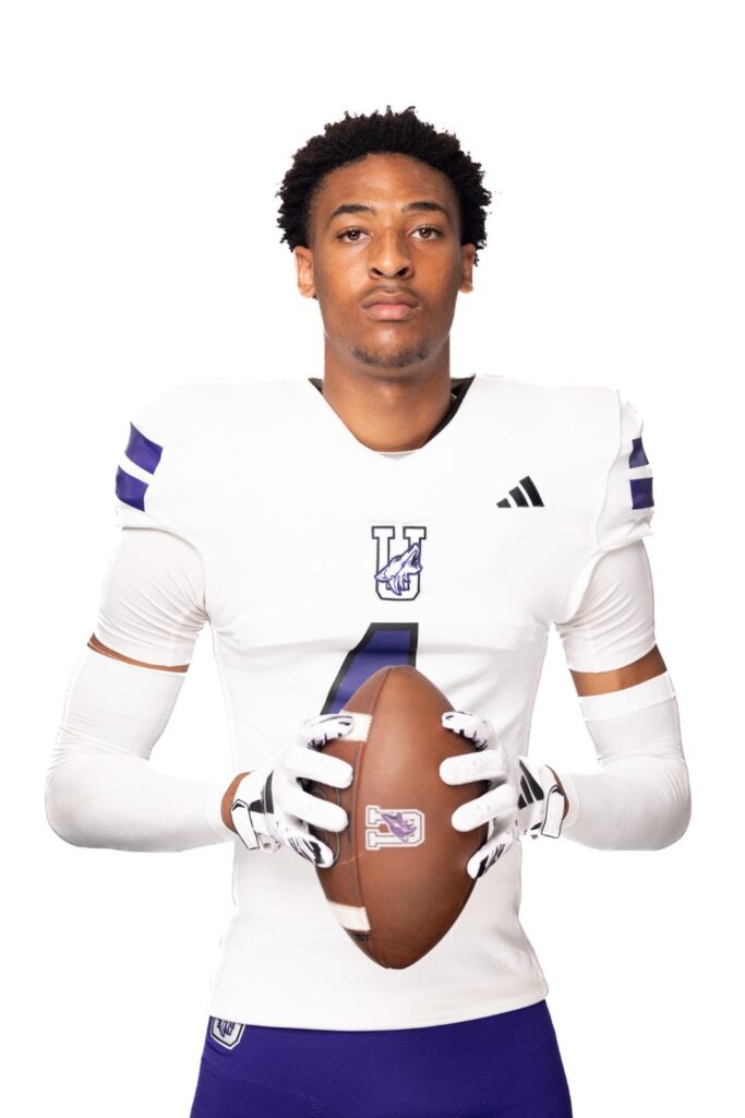 Football player in a white jersey holding a football against a white background