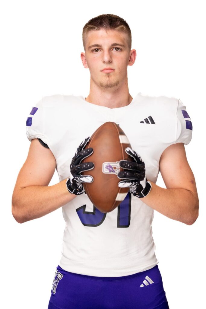 Football player in a white jersey holding a football against a white background
