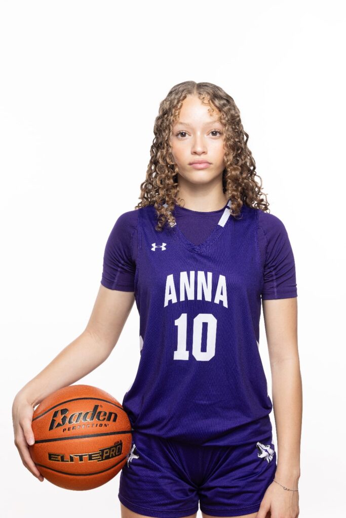 Girls basketball player in a purple number 10 jersey holding a basketball